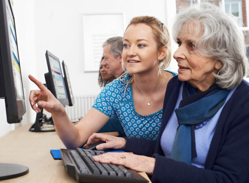 Tutor Helping Senior Woman In Computer Class