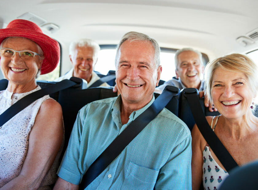 Portrait Of Senior Friends Sitting In Back Of Van Being Driven To Vacation