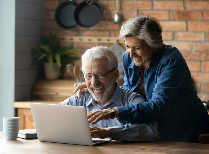 Overjoyed mature couple using laptop together, reading good news