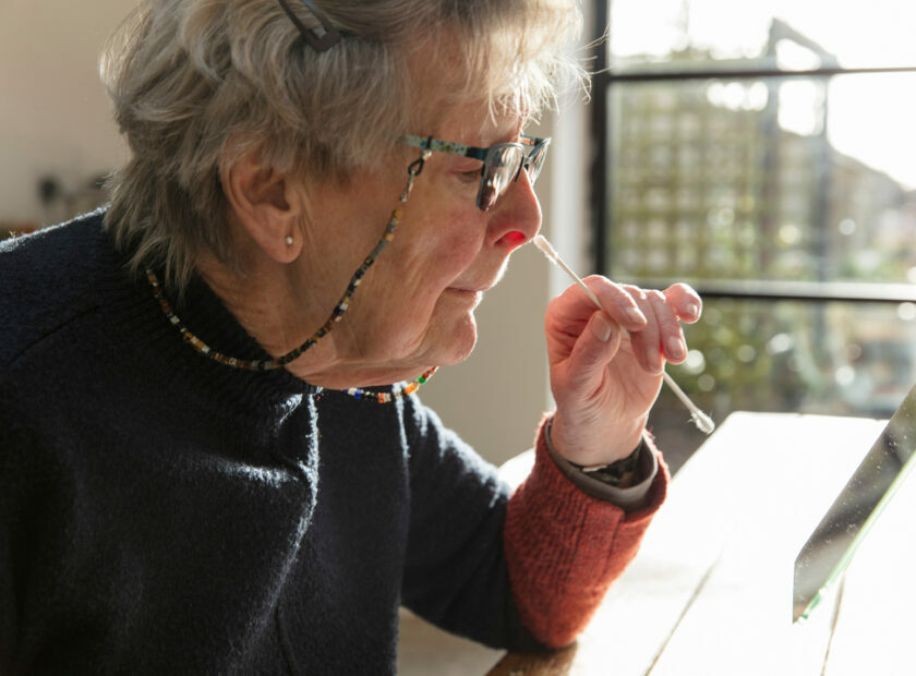 A woman takes a nose sawb at home to test for coronavirus